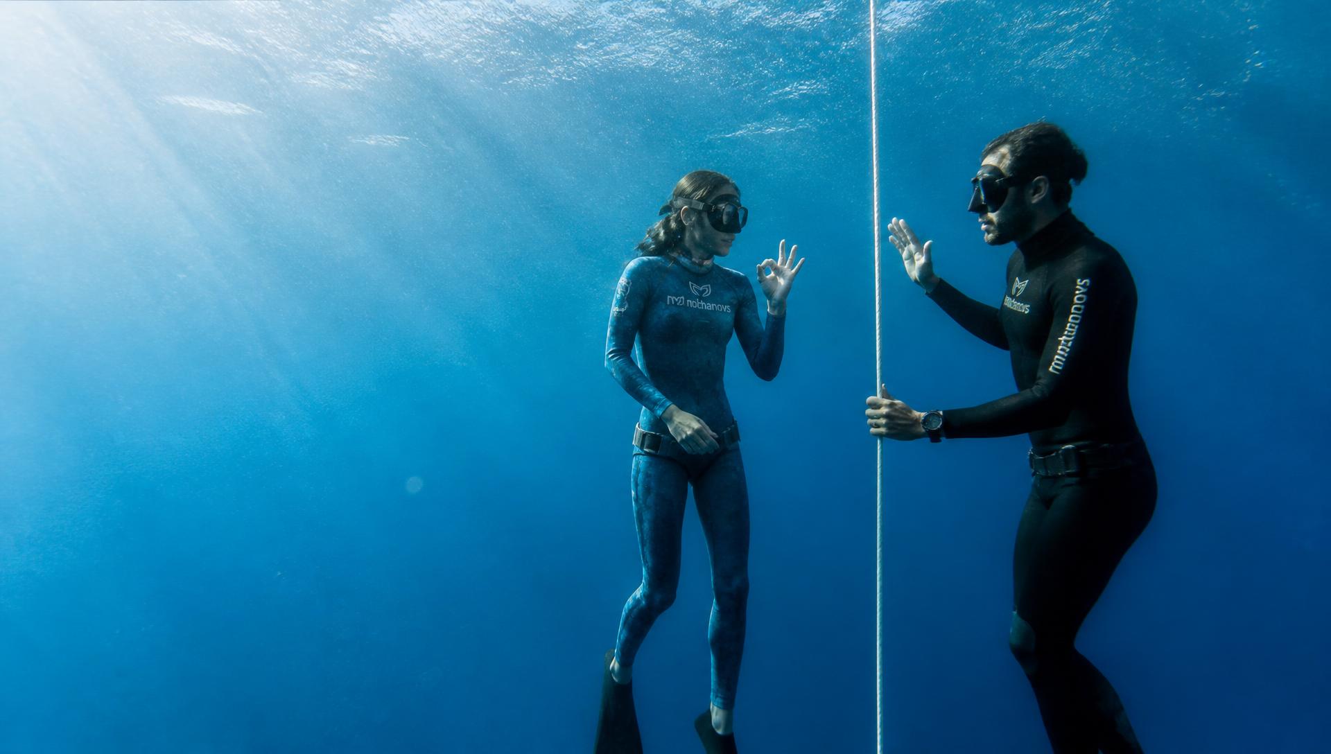 Freediving instructor coaching a student beside a descent line